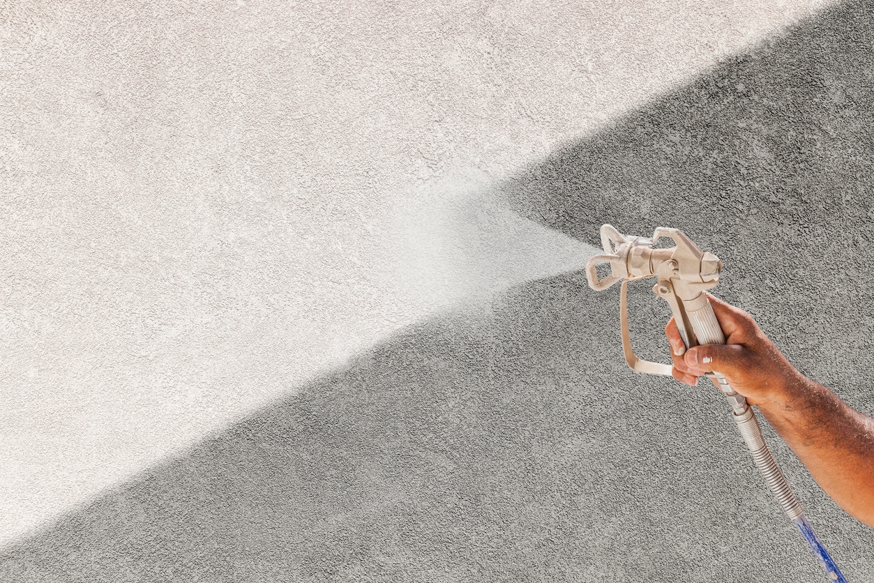 Professional Spray Painter Holding Spray Gun Spraying White Paint Over Grey Stucco Surface in Livermore, CA