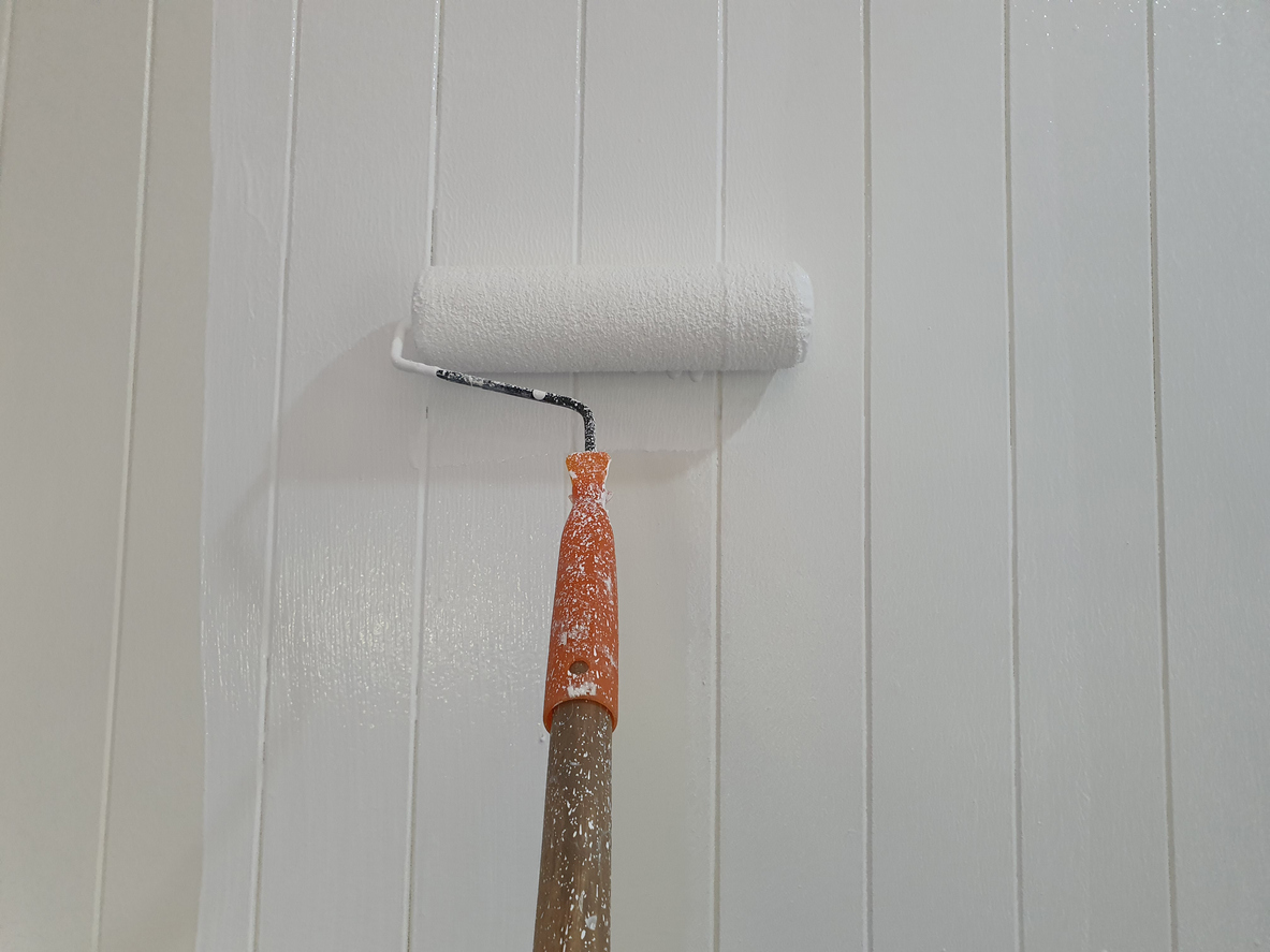 Construction workers use paint roller to prime the left wall