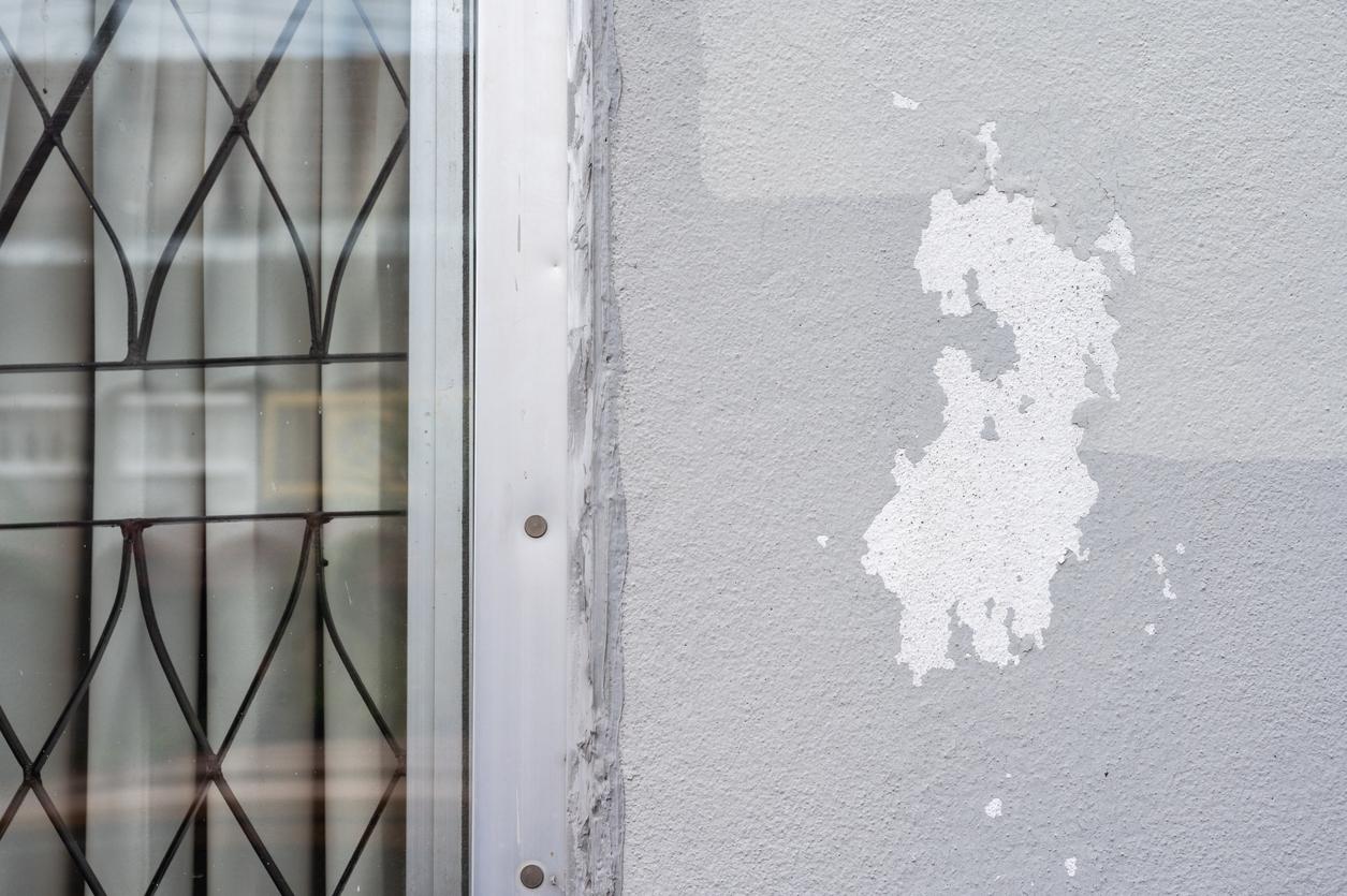 Peeling paint on gray concrete wall.